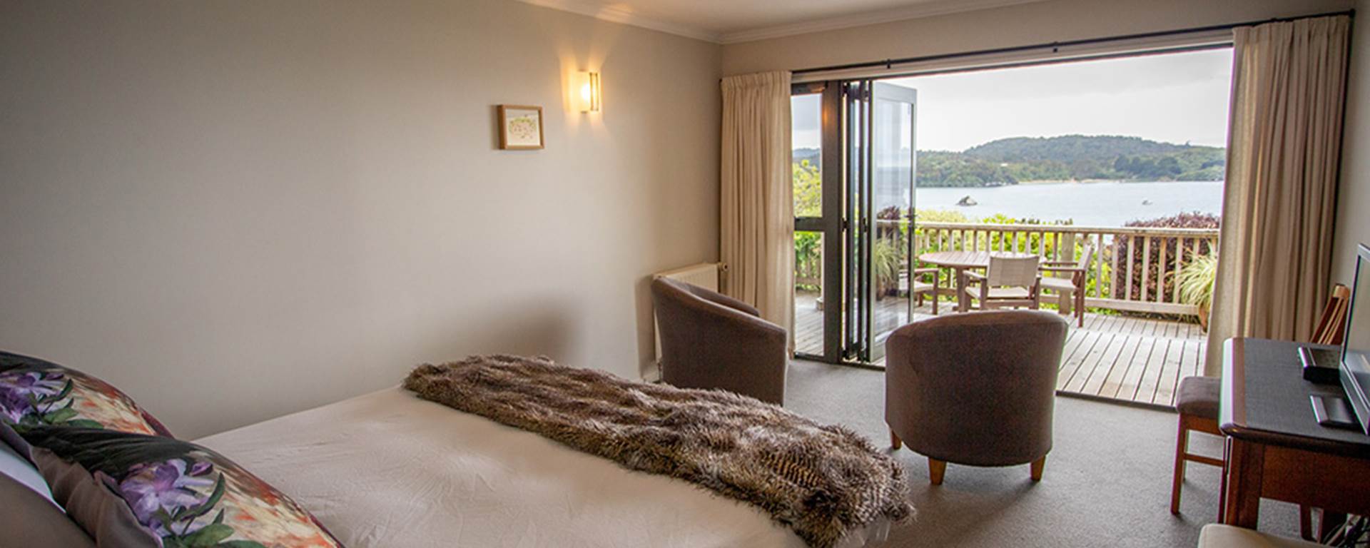 Interior bedroom at the Stewart Island Lodge with doors open on to the balcony