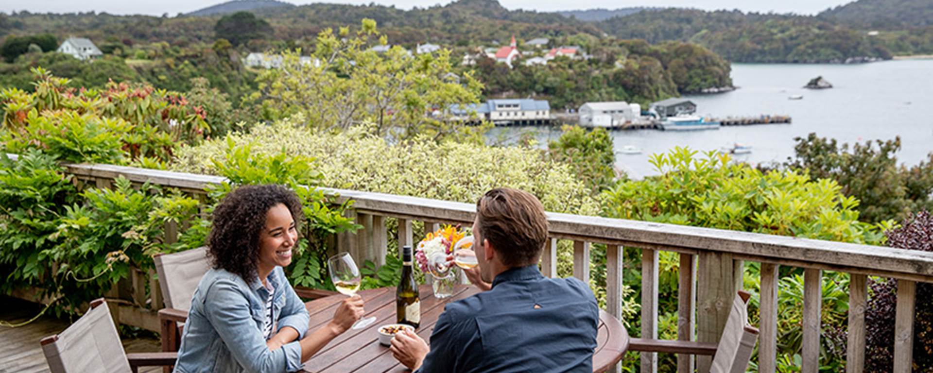 A couple enjoy a bottle of wine on the balcony of the Stewart Island Lodge