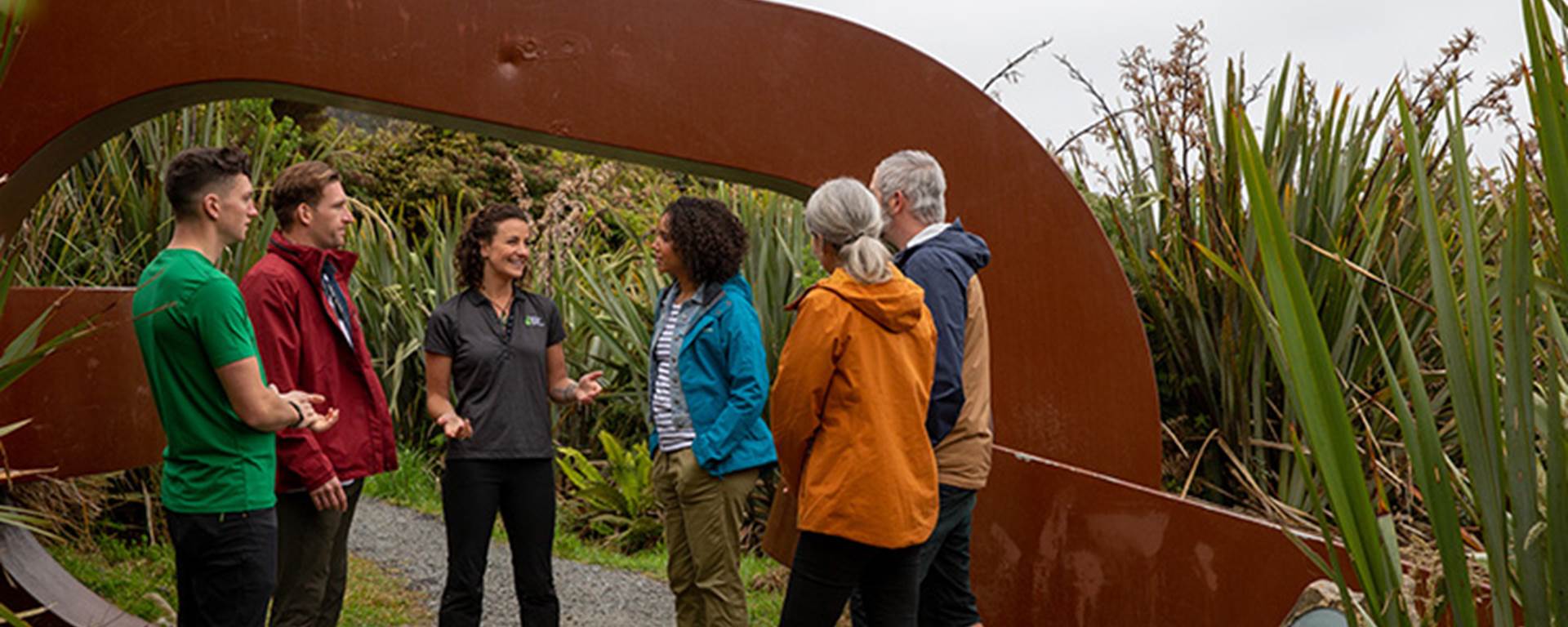 A tour group stop at a landmark on Stewart Island and listen to the guide