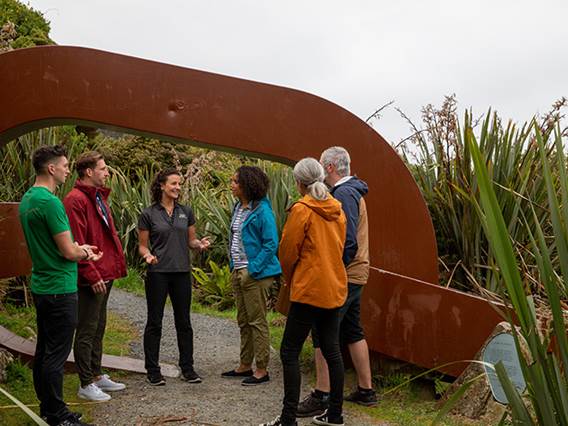 A tour group stop at a landmark on Stewart Island and listen to the guide