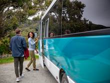 A couple step onto a tour bus on Stewart Island