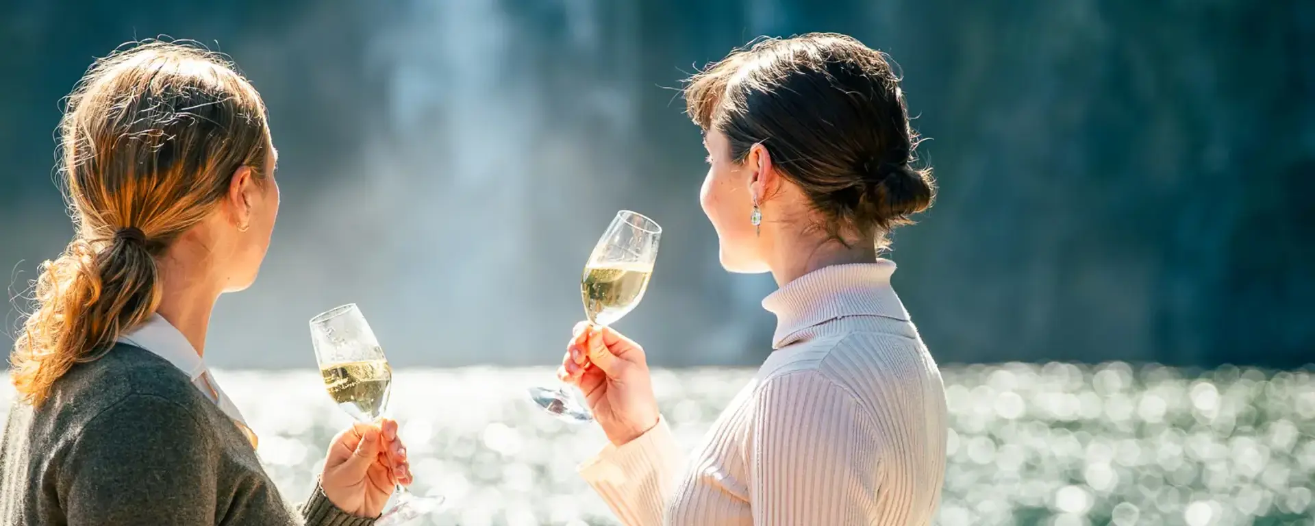 Two guests enjoying drinks with views of Milford Sound.