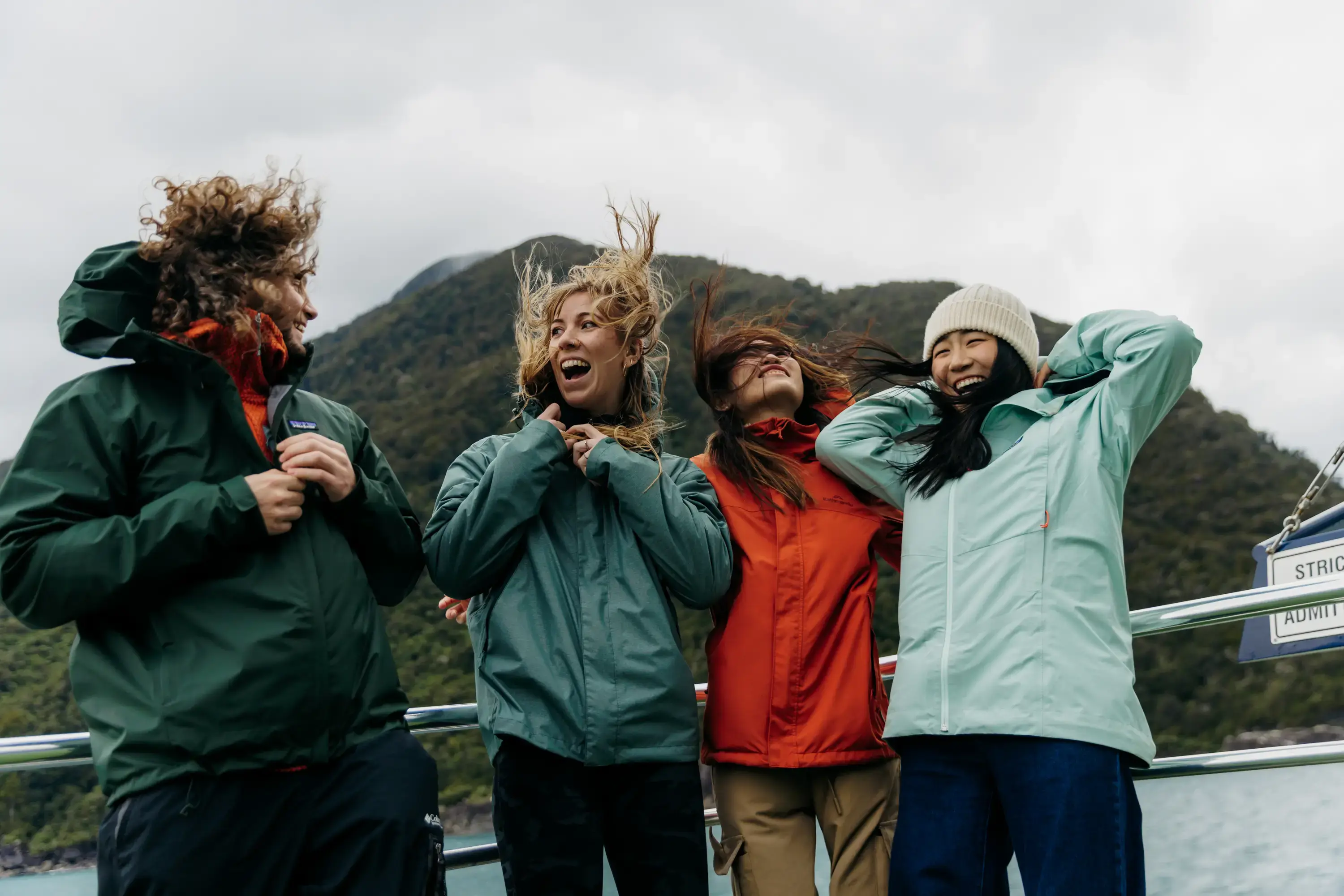 Group of friends laughing together on a Milford Sound cruise.