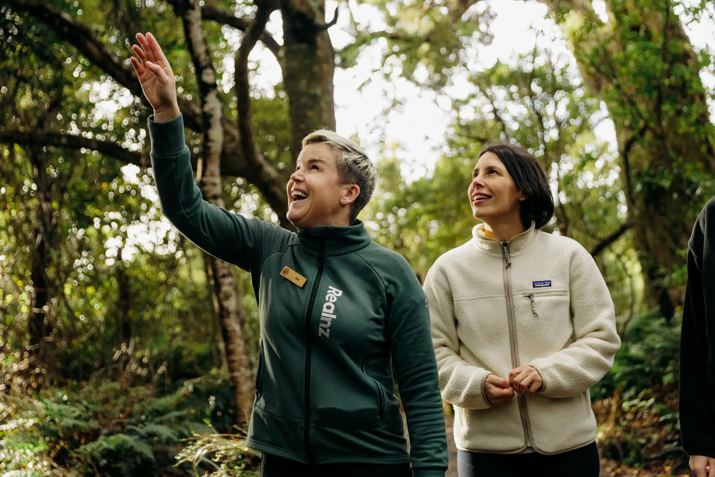 A RealNZ nature guide points out something to a guest in the trees of Ulva Island, on a guided walk through the forrest. 