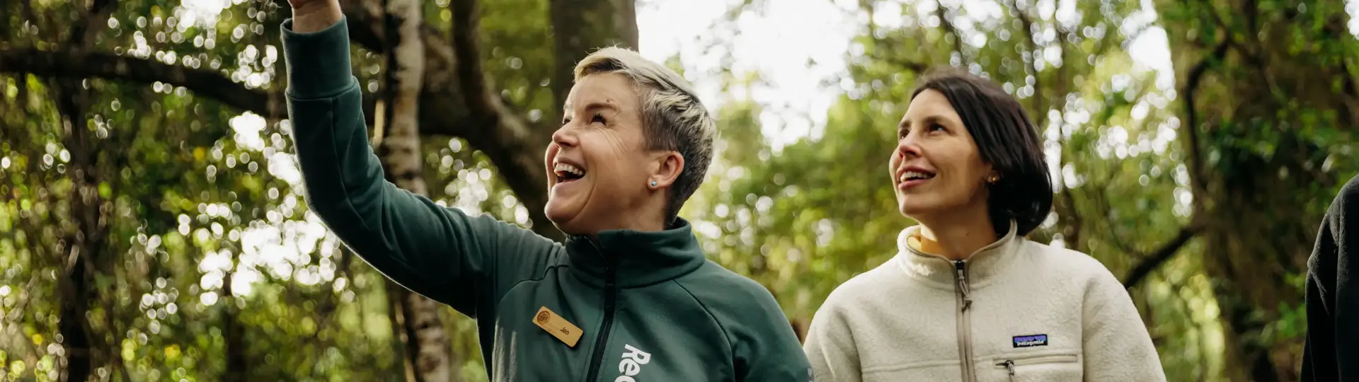 A RealNZ nature guide points out something to a guest in the trees of Ulva Island, on a guided walk through the forrest. 
