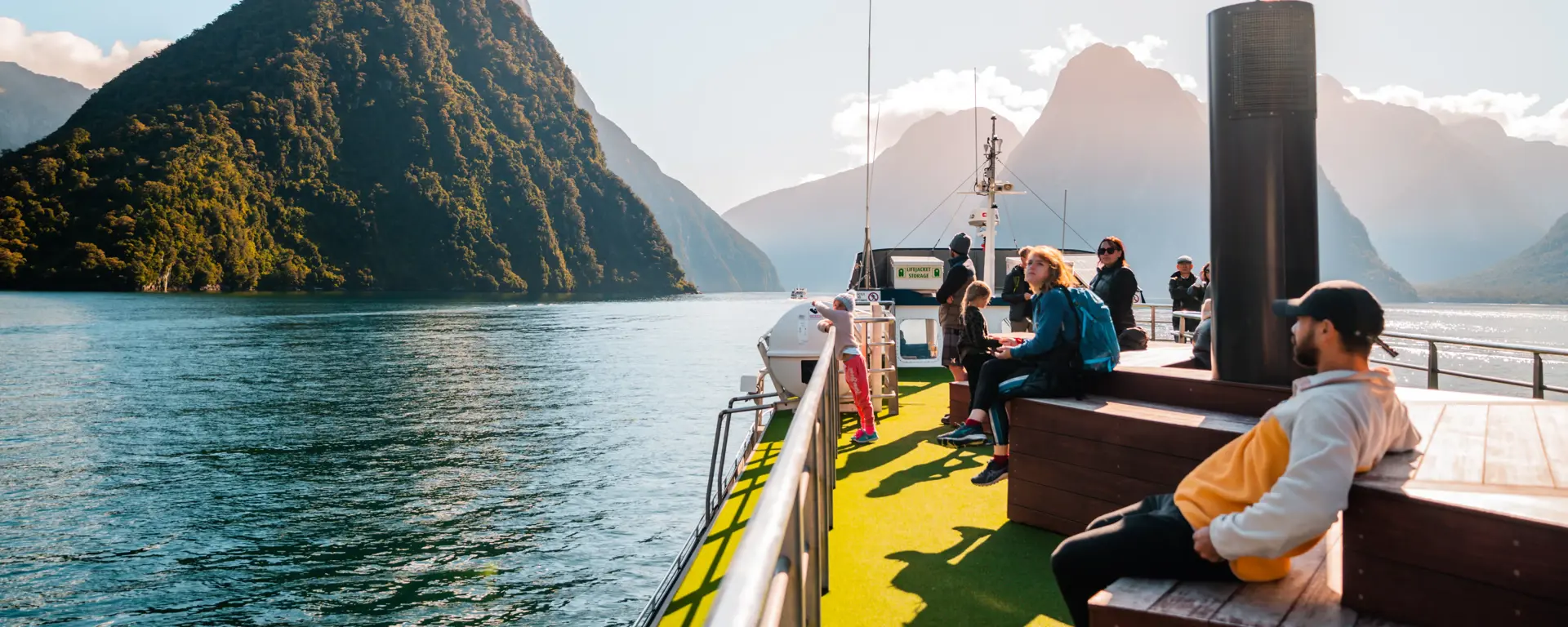 Passengers relaxing on the outdoor deck of a Milford Sound cruise.