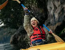 Guest kayaking beneath a waterfall in Doubtful Sound.