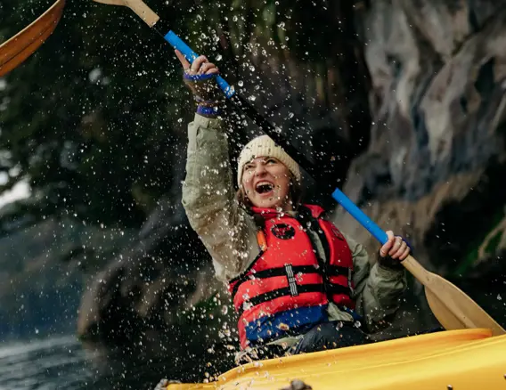 Guest kayaking beneath a waterfall in Doubtful Sound.
