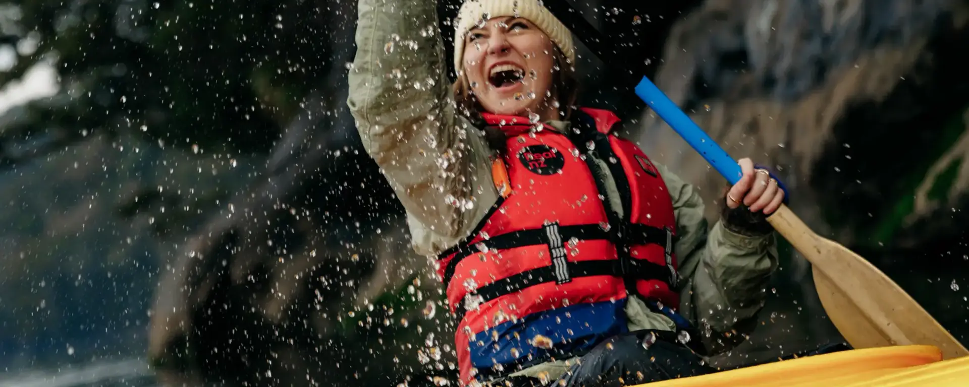 Guest kayaking beneath a waterfall in Doubtful Sound.