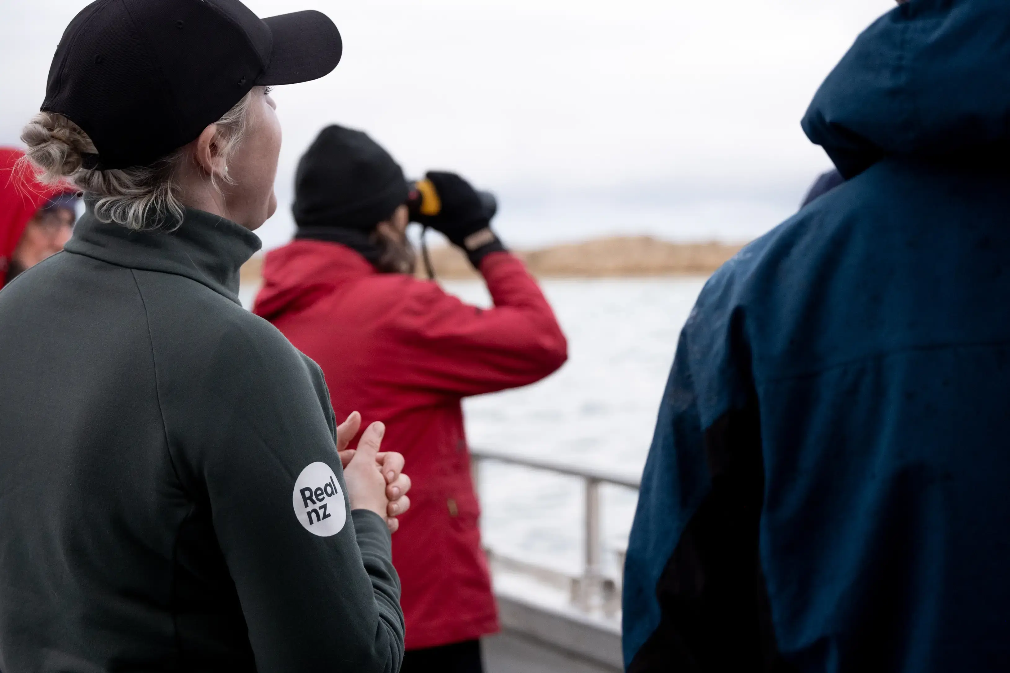 A group of guests try to spot wildlife from a cruise boat, one using binoculars. 