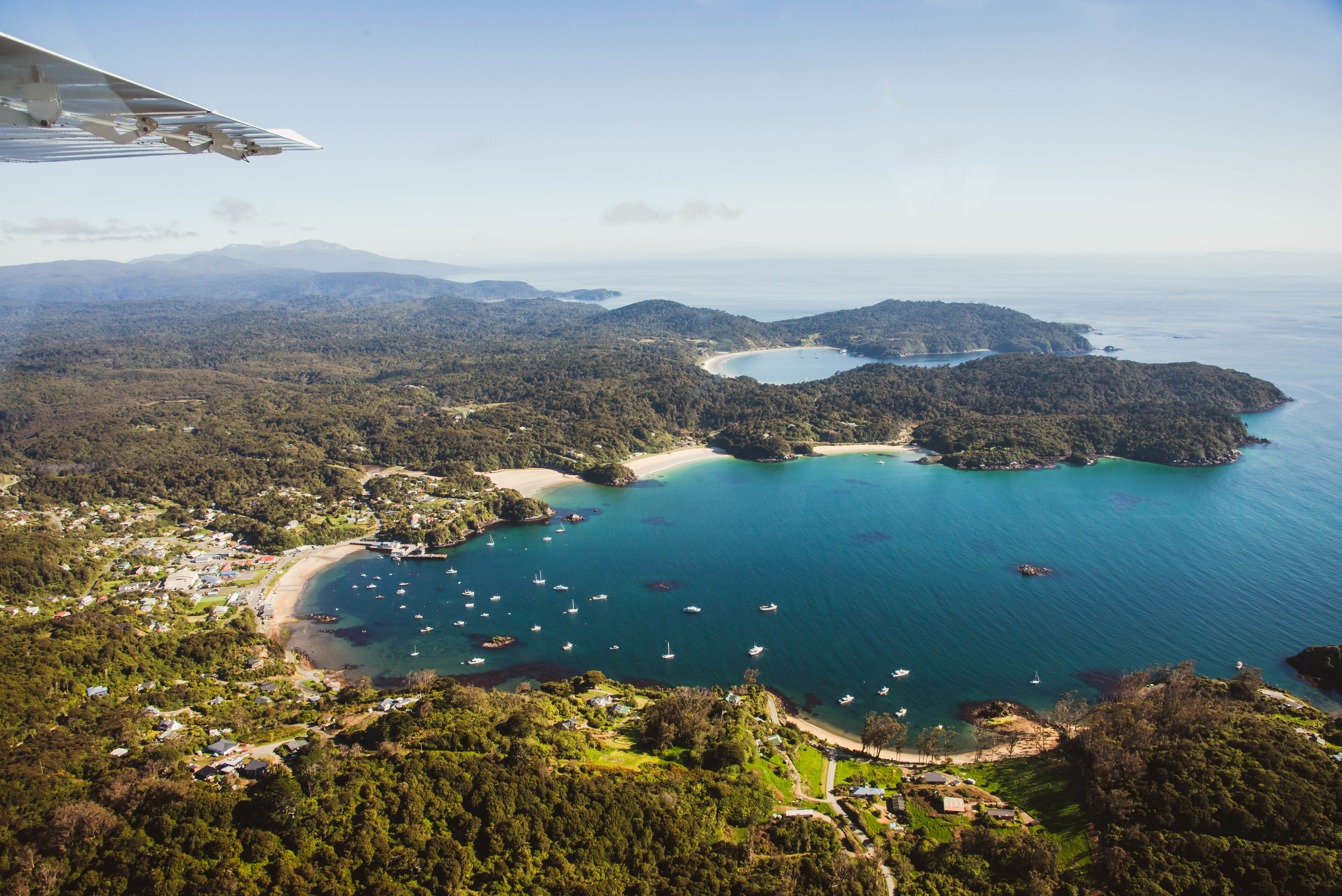 Fly over view of Halfmoon Bay in Oban on Rakiura Stewart Island on a bluebird day.