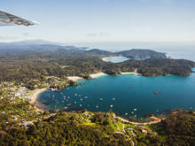 Fly over view of Halfmoon Bay in Oban on Rakiura Stewart Island on a bluebird day.