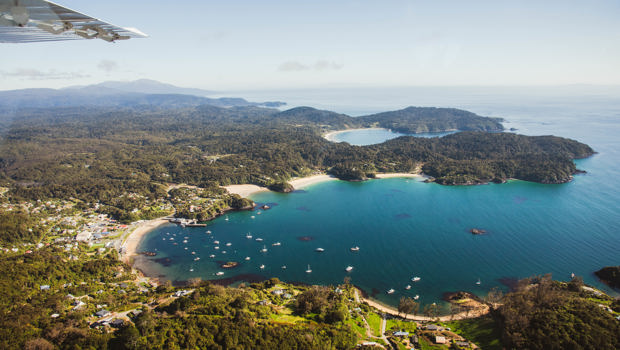 Fly over view of Halfmoon Bay in Oban on Rakiura Stewart Island on a bluebird day.