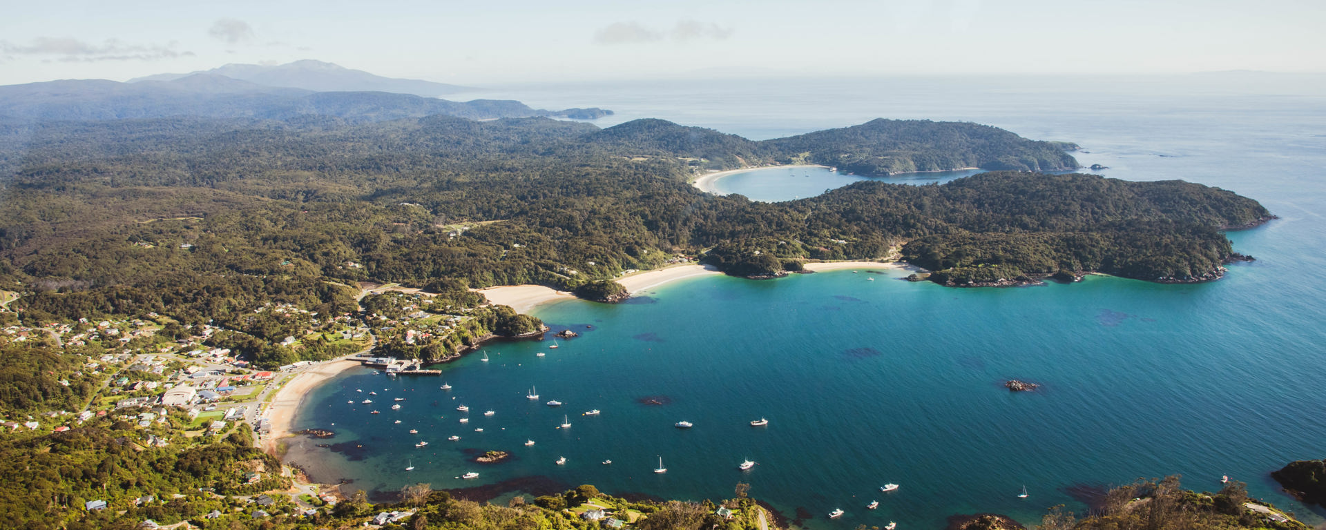 Fly over view of Halfmoon Bay in Oban on Rakiura Stewart Island on a bluebird day.