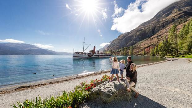 A family views the TSS Earnslaw departing from the Walter Peak shoreline