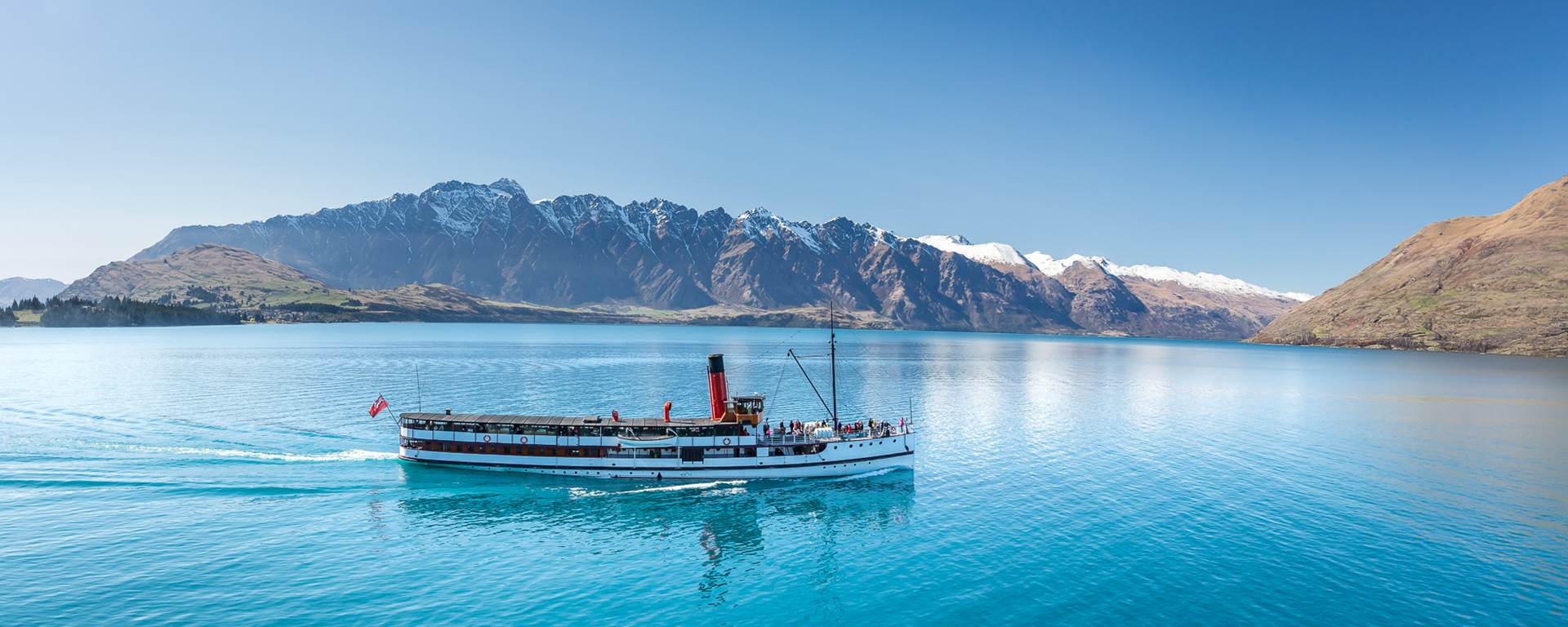 The TSS Earnslaw cruises across Lake Wakatipu with Remarkables in the background