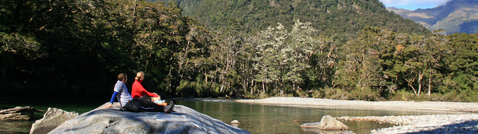 Walkers sit on a rock during the Milford Track Guided Day Walk