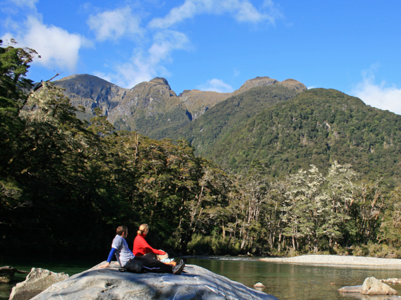 Walkers sit on a rock during the Milford Track Guided Day Walk