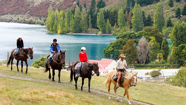 Group on horseback trekking through Walter Peak High Country Farm with views of Lake Wakatipu