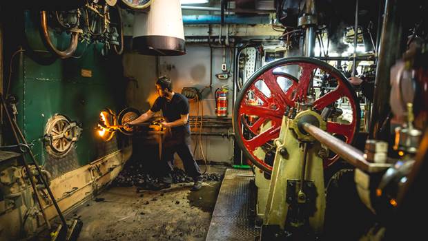Stoker shoveling coal in engine room on the TSS Earnslaw vintage steamship 