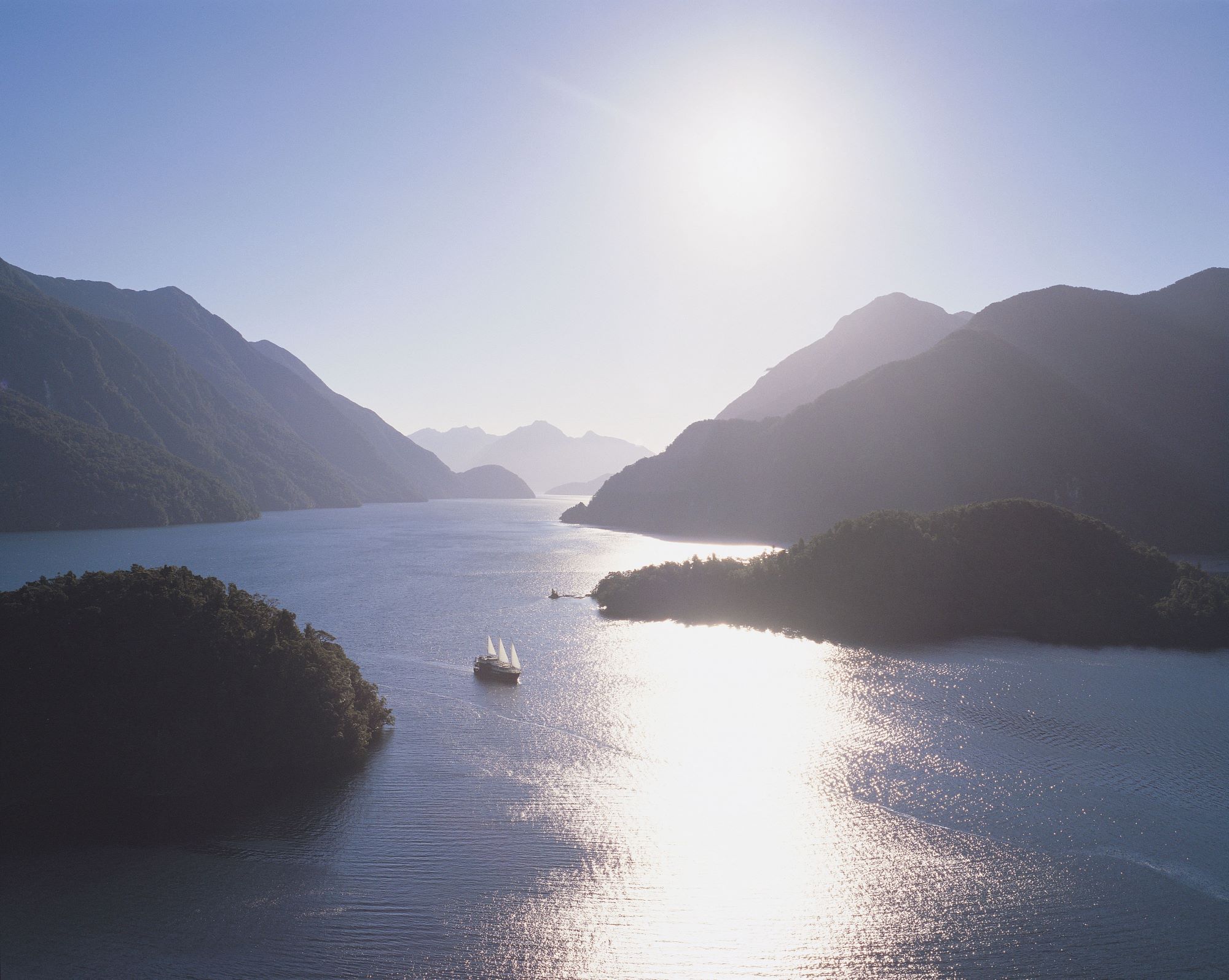 Boat with sails up cruises through Doubtful Sound