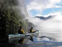 Two kayakers in Doubtful Sound on a misty day