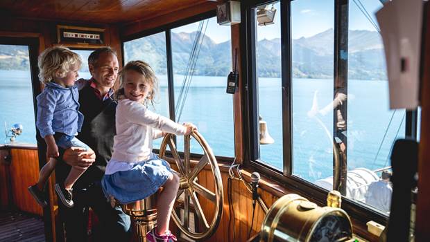 A young girl takes the wheel of the TSS Earnslaw steamship while cruising