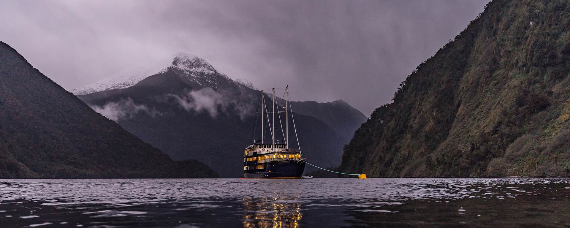 Boat docks of the night in Doubtful Sound with snow-capped mountain
