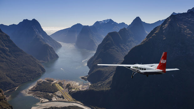Fixed wing airplane approaching Milford Sound on a bluebird day.