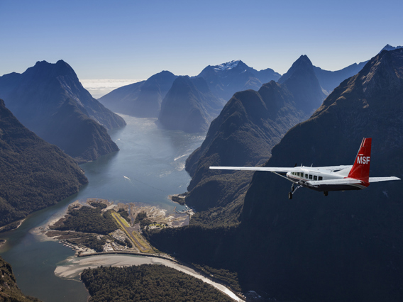 Fixed wing airplane approaching Milford Sound on a bluebird day.