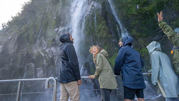 Group under a waterfall in Milford Sound
