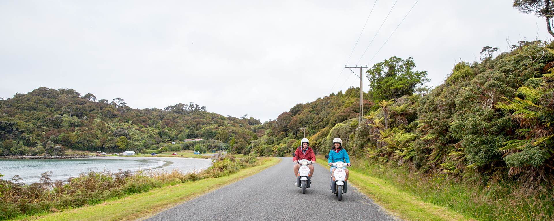 Two people on scooter on Stewart Island coastal road