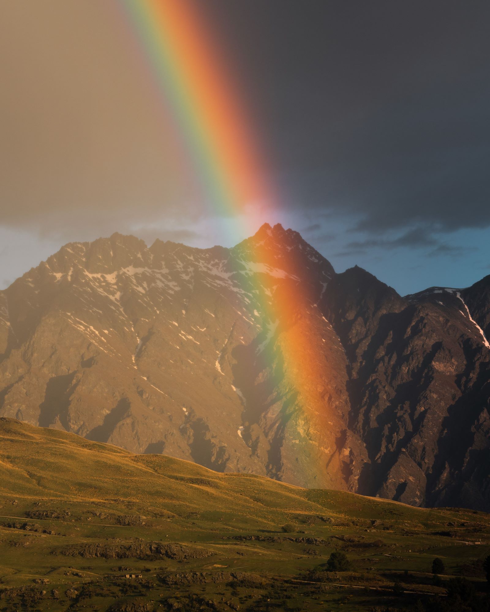 A rainbow shines in front of The Remarkables mountain range in Queenstown