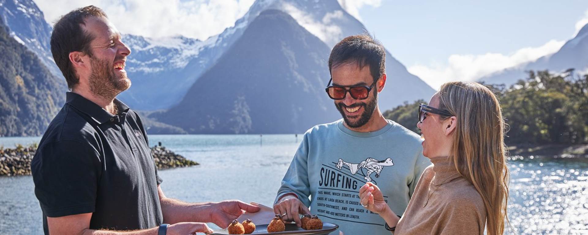Couple eating canapes in front of Mitre Peak