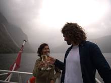 A couple clinking champagne glasses on Milford Sound