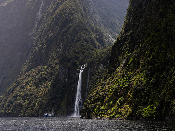 The Milford Mariner boat cruises close to a cascading waterfall in Milford Sound