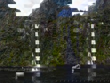 Wide shot of The Sovereign boat cruising in front of a waterfall on Milford Sound