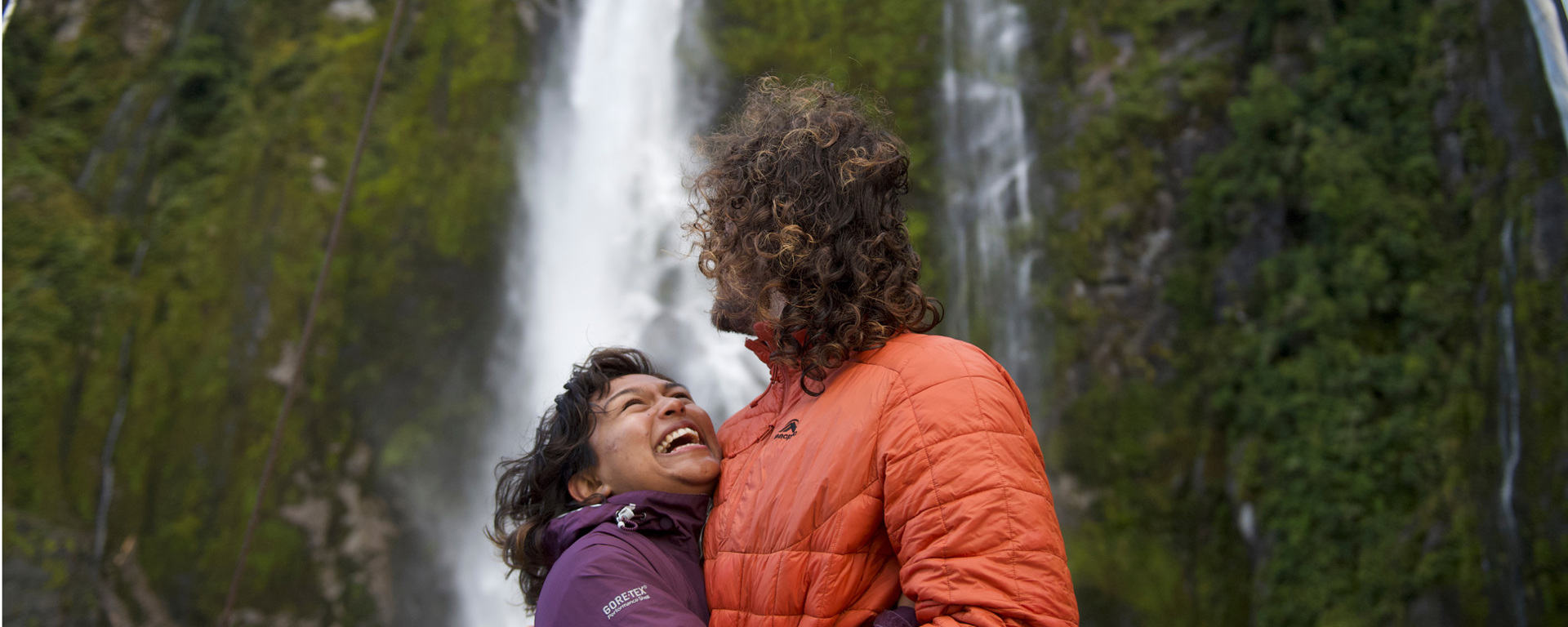 A couple hugging in front of a waterfall