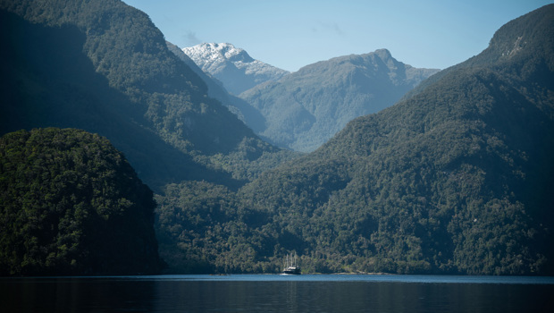 Wide shot of the Fiordland Navigator cruising through Doubtful Sound, surrounded by mountains