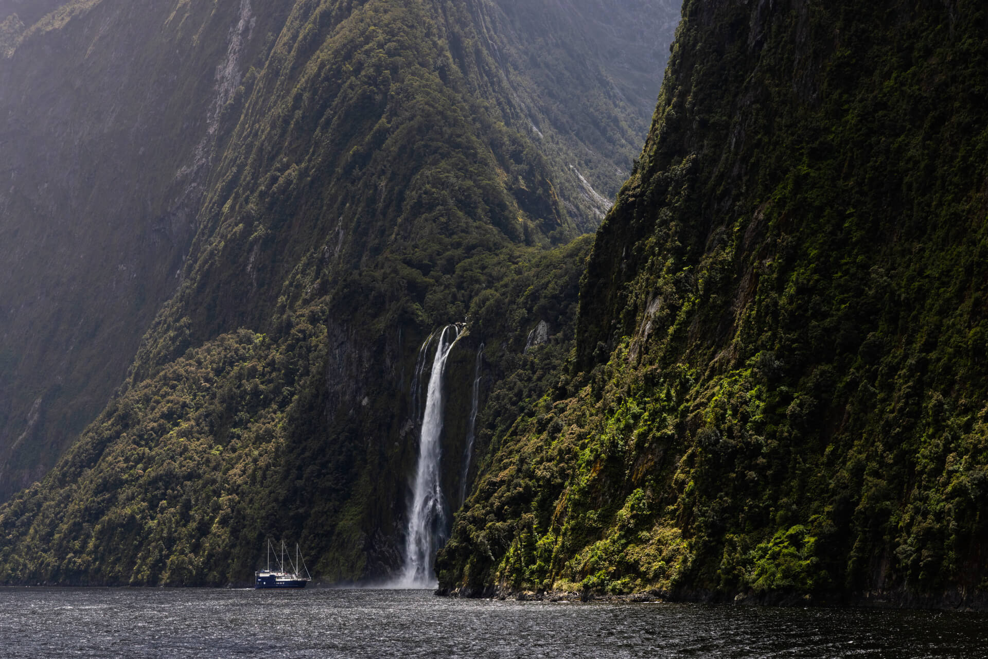 A large sailboat approaches the famous Stirling Falls in Milford Sound, NZ.