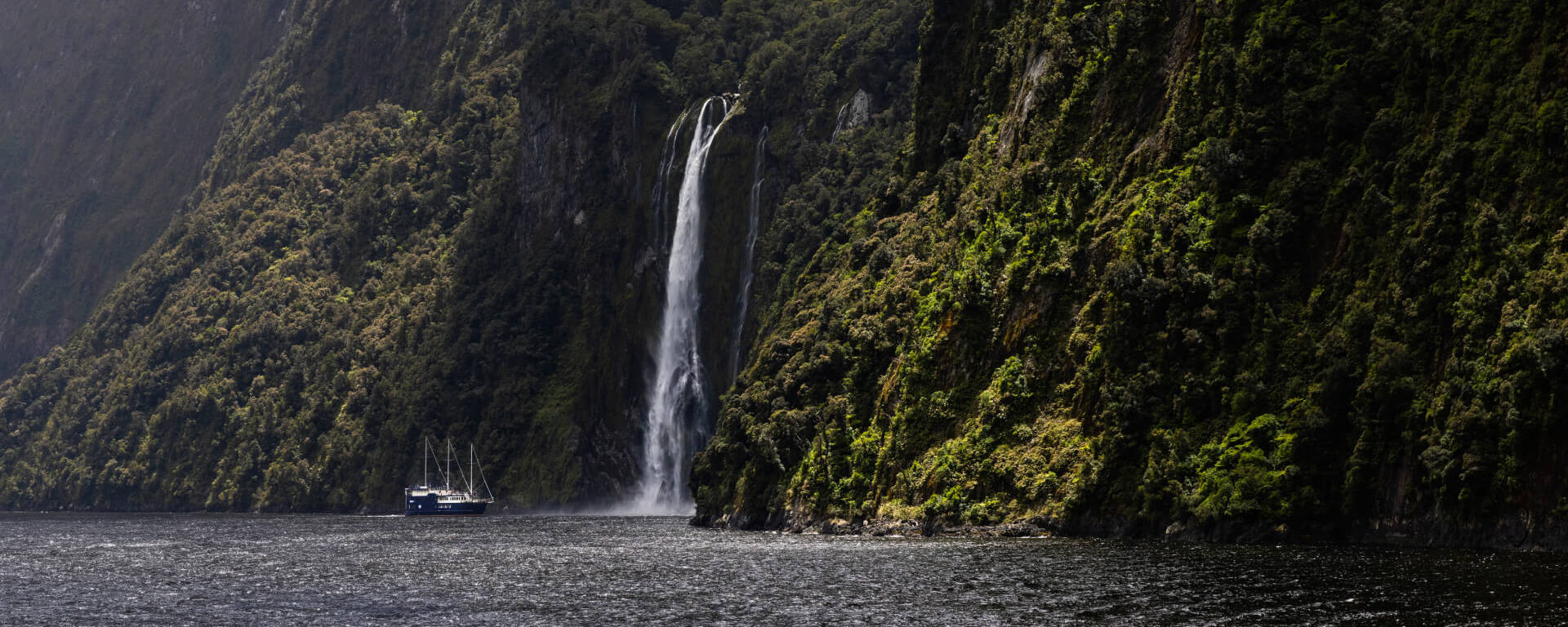 A large sailboat approaches the famous Stirling Falls in Milford Sound, NZ.