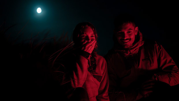Couple searching for kiwi under a full moon
