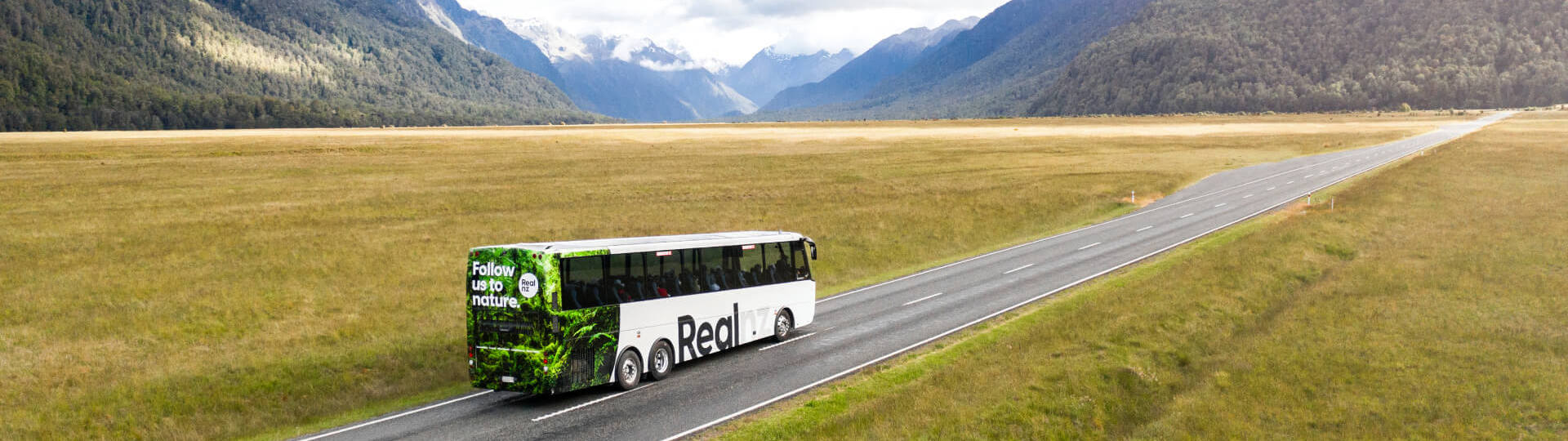 A bus drives through the Eglinton Valley on its way to Milford Sound.