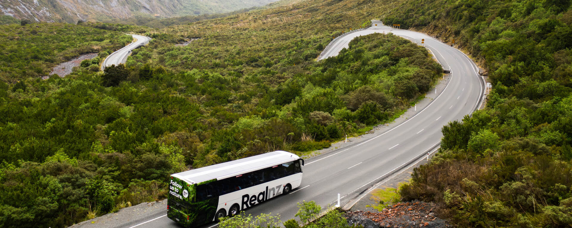 A bus drives down a scenic and windy section of road on the last approach to Milford Sound.