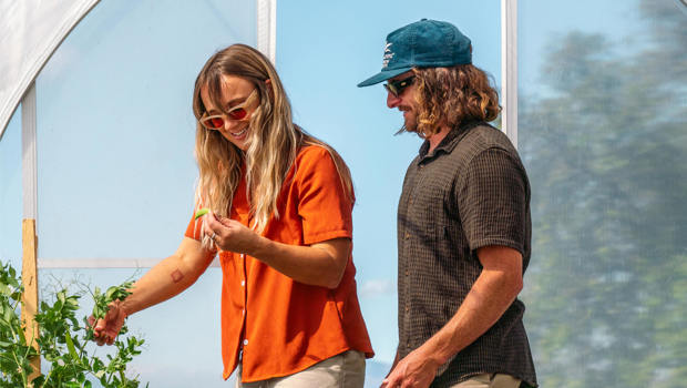 A couple explores Walter Peak’s Garden to Table Experience greenhouse, harvesting fresh vegetables and enjoying a hands-on sustainable experience.