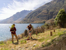 Guests participate in tree planting at Walter Peak’s Garden to Table Experience, set against a stunning lake and mountain backdrop.