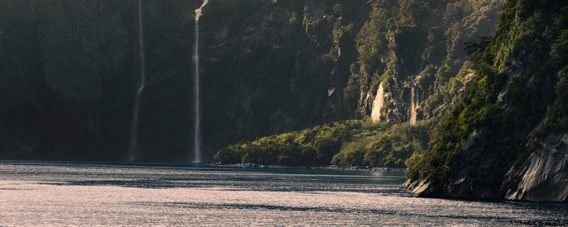 A panoramic photo of Milford Sound with waterfalls cascading into the fiord.