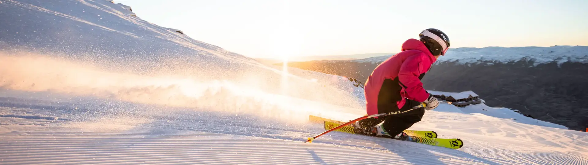 Skier carving across a groomed snowy slope at Cardrona Alpine Resort.