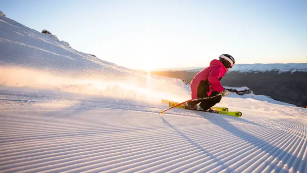Skier carving across a groomed snowy slope at Cardrona Alpine Resort.
