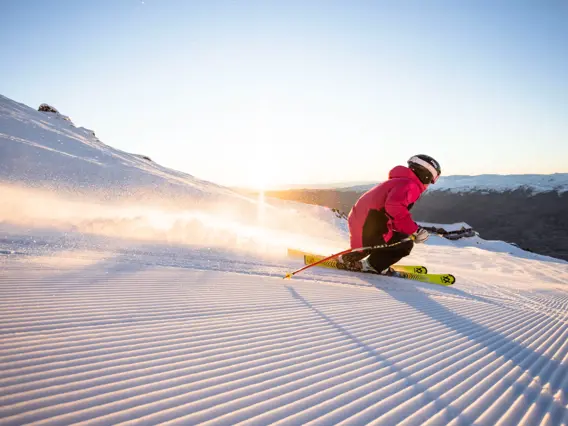 Skier carving across a groomed snowy slope at Cardrona Alpine Resort.
